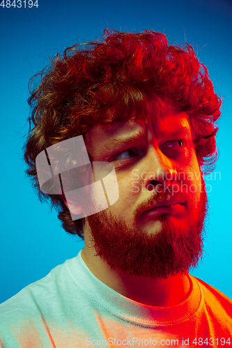 Image of Caucasian close up man\'s portrait isolated on blue studio background in neon light