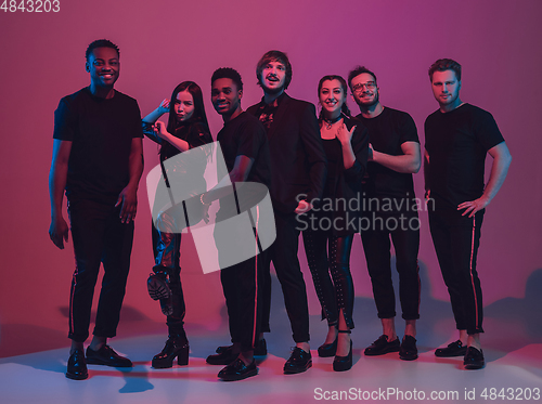 Image of Group of young multiethnic musicians created band, dancing in neon light on pink background