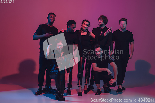 Image of Group of young multiethnic musicians created band, dancing in neon light on pink background
