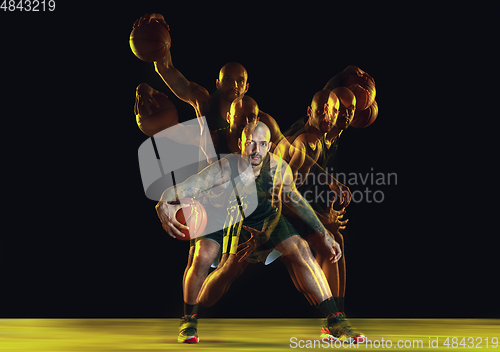 Image of Young basketball player training on dark studio background in neon, strobe light