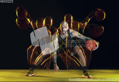 Image of Young basketball player training on dark studio background in neon, strobe light