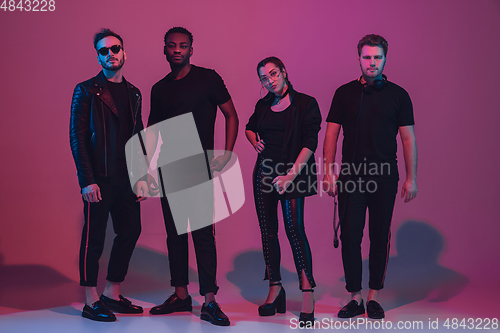 Image of Group of young multiethnic musicians created band, dancing in neon light on pink background