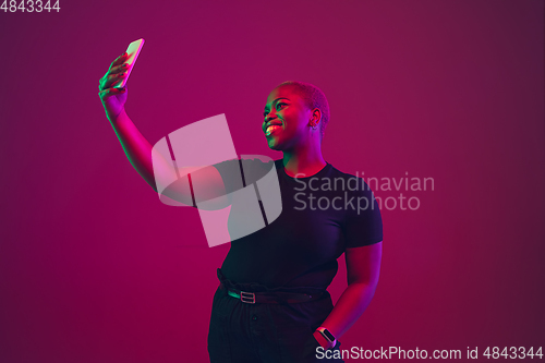 Image of African-american young woman\'s portrait on purple pink background