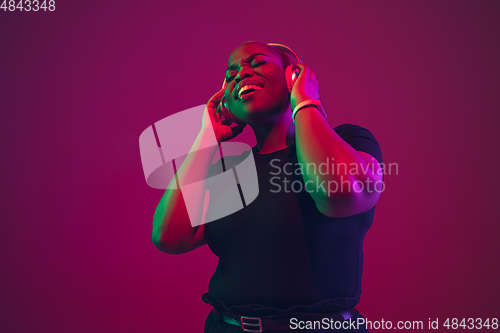 Image of African-american young woman\'s portrait on purple pink background