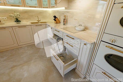 Image of Open drawer in cabinet at luxury beige and gold classic kitchen furniture