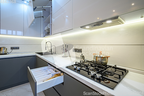 Image of Luxury white and dark grey modern kitchen interior with open drawer