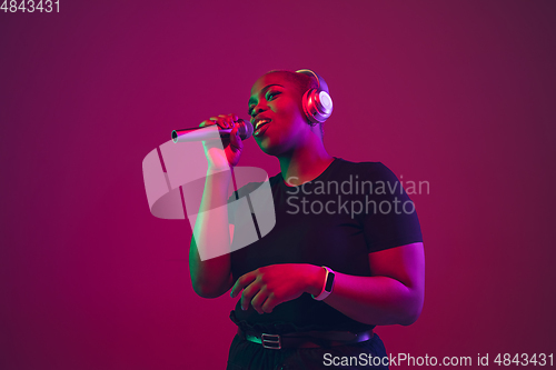 Image of African-american young woman\'s portrait on purple pink background