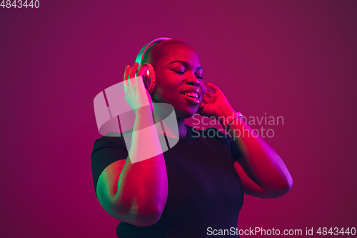 Image of African-american young woman\'s portrait on purple pink background