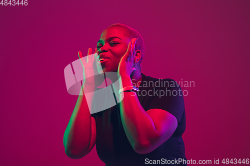 Image of African-american young woman\'s portrait on purple pink background