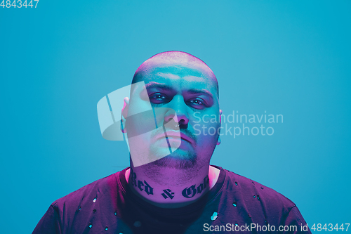 Image of Portrait of a hipster guy with colorful neon light on blue background