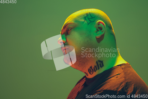 Image of Portrait of a hipster guy with colorful neon light on green background