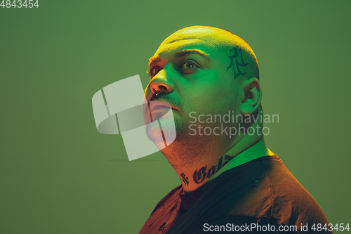 Image of Portrait of a hipster guy with colorful neon light on green background