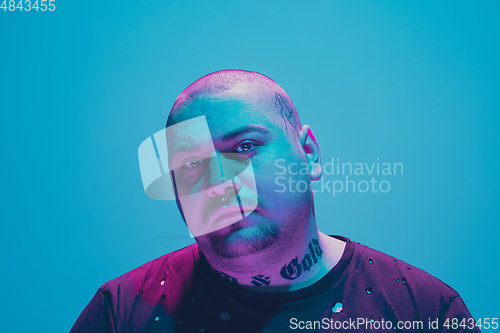 Image of Portrait of a hipster guy with colorful neon light on blue background