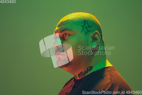 Image of Portrait of a hipster guy with colorful neon light on green background