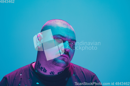 Image of Portrait of a hipster guy with colorful neon light on blue background