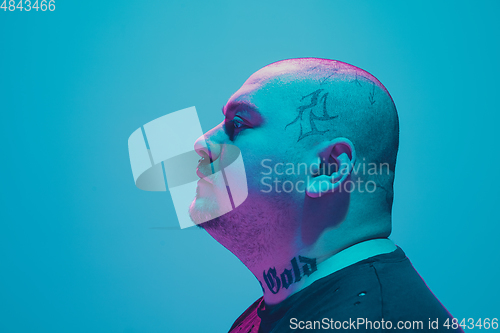 Image of Portrait of a hipster guy with colorful neon light on blue background