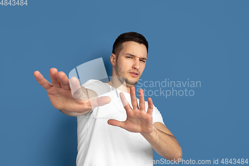 Image of Caucasian young man\'s portrait on blue studio background