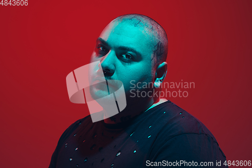 Image of Portrait of a guy with colorful neon light on red background - cyberpunk concept