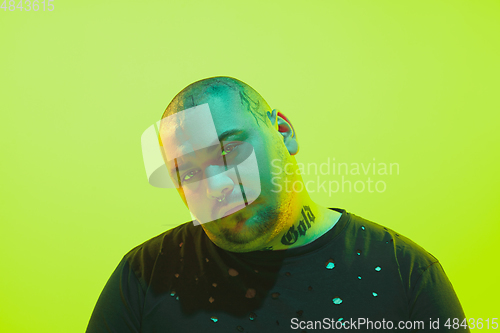 Image of Portrait of a guy with colorful neon light on green background