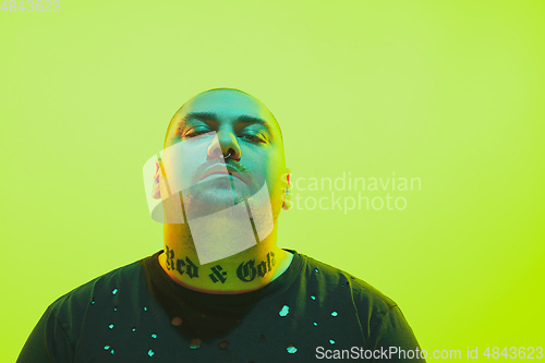 Image of Portrait of a guy with colorful neon light on green background