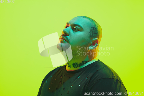 Image of Portrait of a guy with colorful neon light on green background