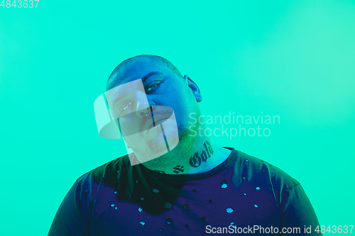 Image of Portrait of a guy with colorful neon light on green background