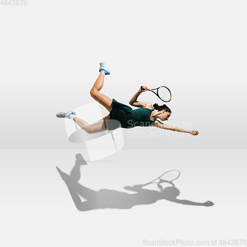 Image of Young caucasian professional sportswoman levitating, flying while playing tennis isolated on white background