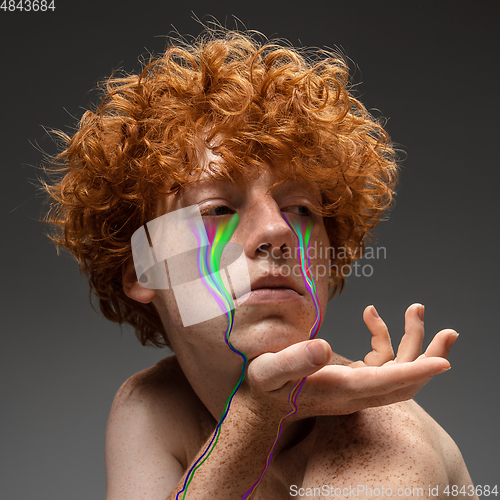 Image of Portrait of young beautiful man with neon, fluid tears from eyes. Concept of fashion and beauty, emotions and feelings, modern design