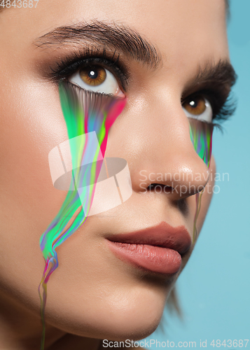 Image of Portrait of young beautiful woman with neon, fluid tears from eyes. Concept of fashion and beauty, emotions and feelings, modern design