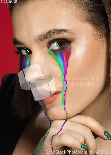 Image of Portrait of young beautiful woman with neon, fluid tears from eyes. Concept of fashion and beauty, emotions and feelings, modern design