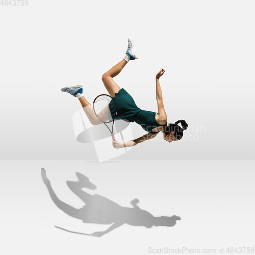 Image of Young caucasian professional sportswoman levitating, flying while playing tennis isolated on white background