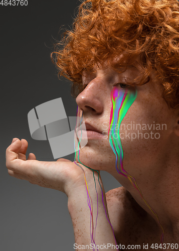 Image of Portrait of young beautiful man with neon, fluid tears from eyes. Concept of fashion and beauty, emotions and feelings, modern design