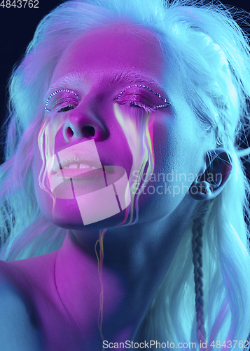 Image of Portrait of young beautiful woman with neon, fluid tears from eyes. Concept of fashion and beauty, emotions and feelings, modern design