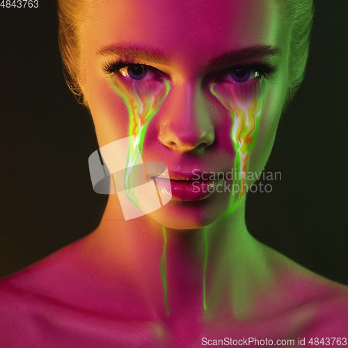 Image of Portrait of young beautiful woman with neon, fluid tears from eyes. Concept of fashion and beauty, emotions and feelings, modern design