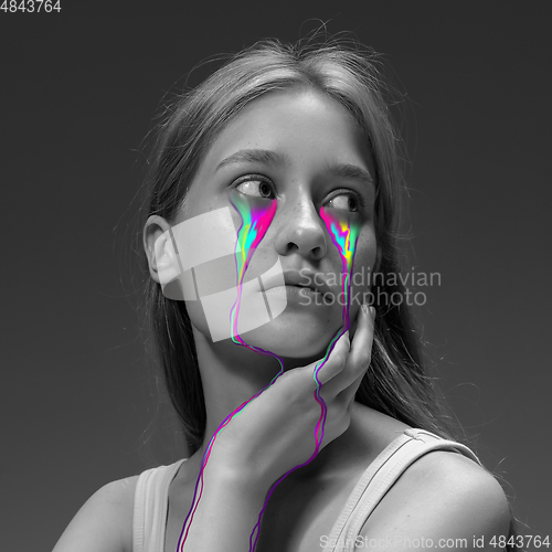 Image of Portrait of young beautiful woman with neon, fluid tears from eyes. Concept of fashion and beauty, emotions and feelings, modern design