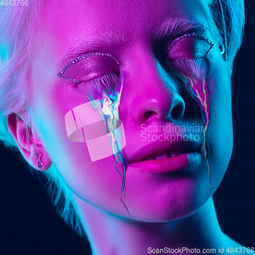 Image of Portrait of young beautiful woman with neon, fluid tears from eyes. Concept of fashion and beauty, emotions and feelings, modern design