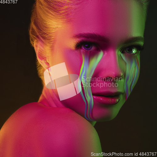 Image of Portrait of young beautiful woman with neon, fluid tears from eyes. Concept of fashion and beauty, emotions and feelings, modern design