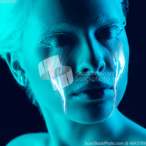 Image of Portrait of young beautiful woman with neon, fluid tears from eyes. Concept of fashion and beauty, emotions and feelings, modern design