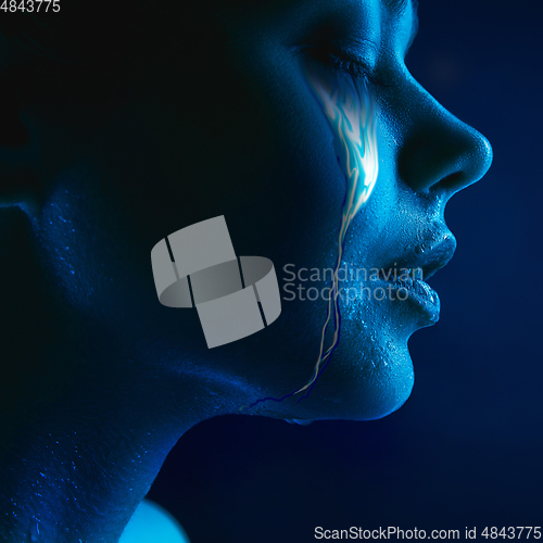 Image of Portrait of young beautiful woman with neon, fluid tears from eyes. Concept of fashion and beauty, emotions and feelings, modern design