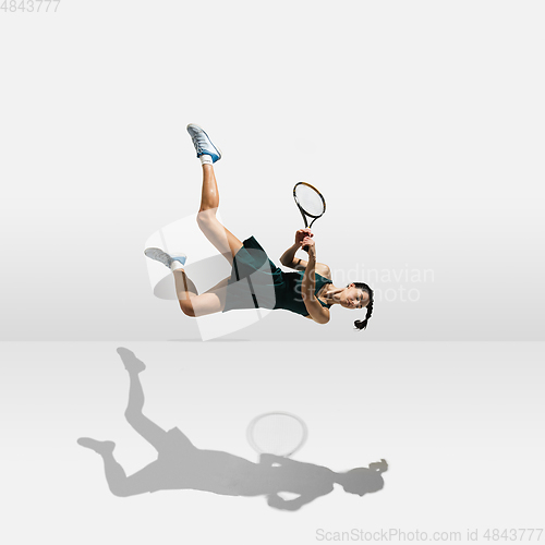 Image of Young caucasian professional sportswoman levitating, flying while playing tennis isolated on white background