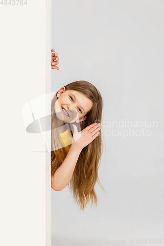 Image of Happy kid, girl isolated on white studio background. Looks happy, cheerful, sincere. Copyspace. Childhood, education, emotions concept