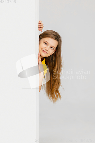 Image of Happy kid, girl isolated on white studio background. Looks happy, cheerful, sincere. Copyspace. Childhood, education, emotions concept