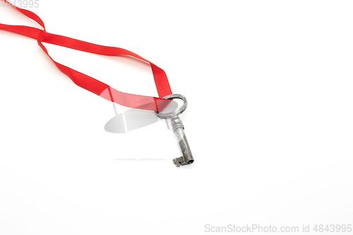 Image of Vintage silver key on red ribbon on white background