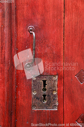 Image of Vintage red wooden door with metallic handle and keyholes