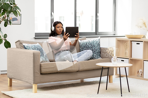 Image of woman with tablet pc listening to music at home