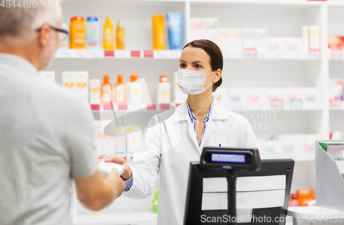 Image of apothecary in mask and senior customer at pharmacy