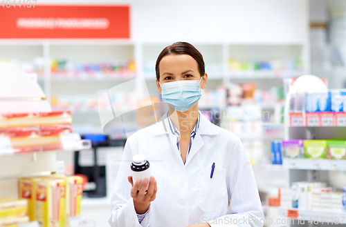 Image of female apothecary in mask with drug at pharmacy