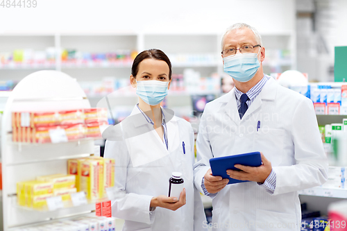 Image of apothecaries in masks with tablet pc at pharmacy