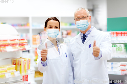 Image of apothecaries in masks show thumbs up at pharmacy