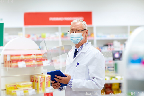 Image of old apothecary in mask with tablet pc at pharmacy